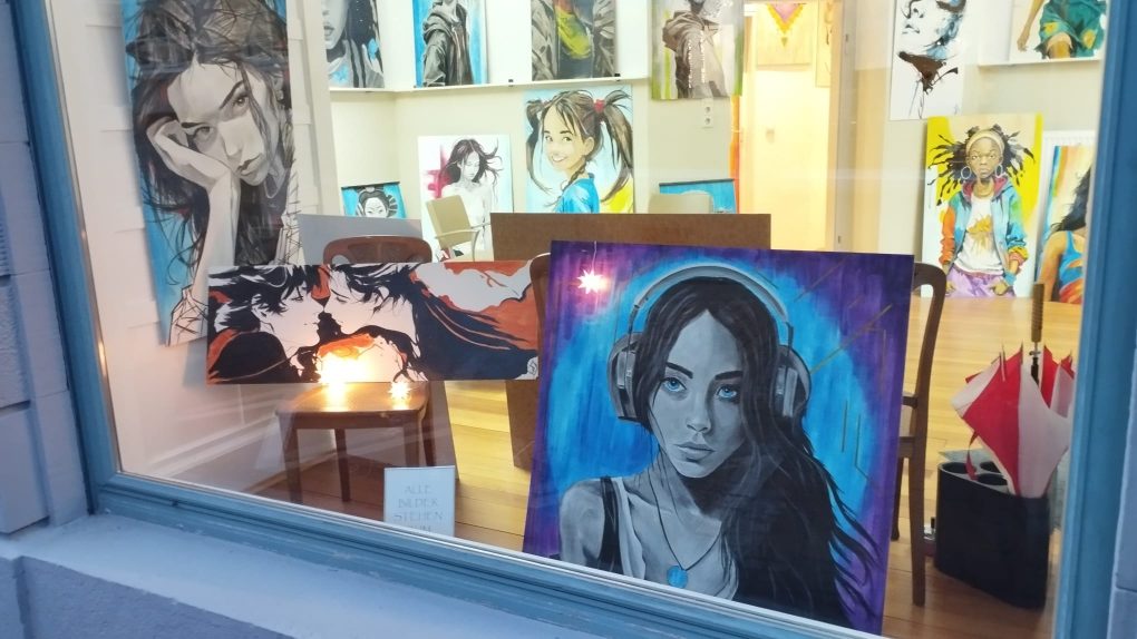 Künstlerische Ölgemälde, farbenfroh und schwarz-weiss, Portraits von Frauen in verscheidenen Stilrichtungen im Schaufenster bei Inskin Tattoo Radolfzell